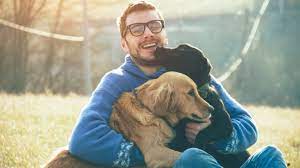 man hugging two dogs